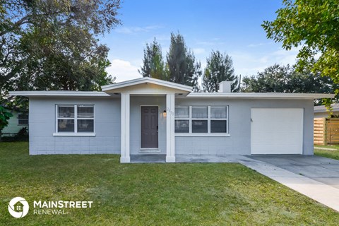 a small white house with a driveway and grass